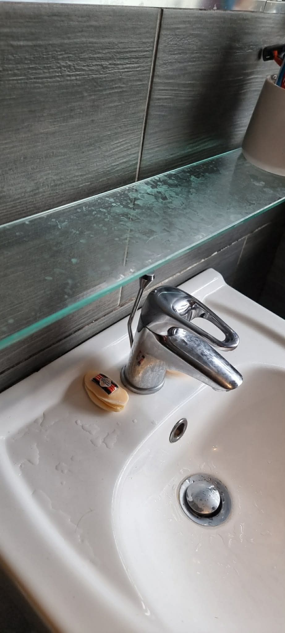 Bathroom basin, tap and glass shelf before cleaning